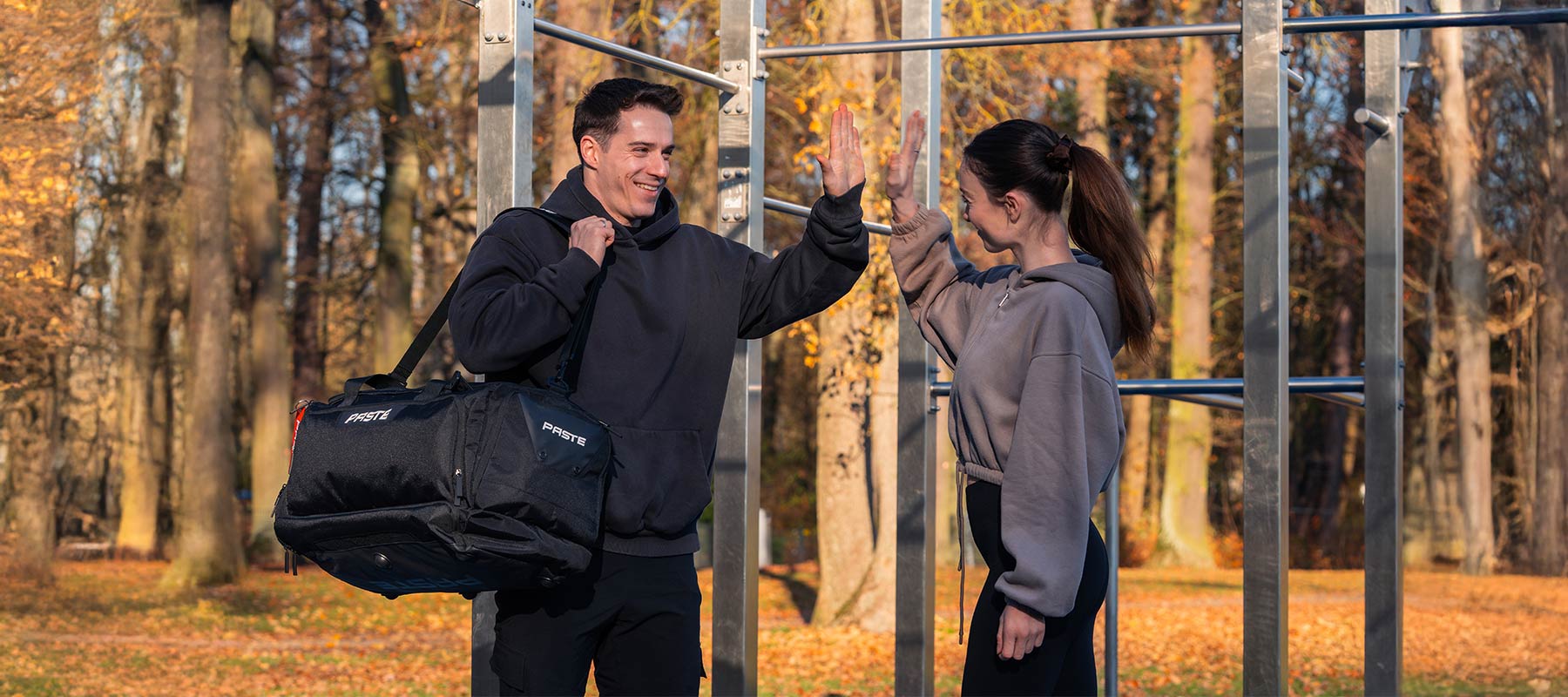Zwei Sportler beim Outdoor-Training mit einer PASTE Sporttasche an einer Calisthenics-Anlage